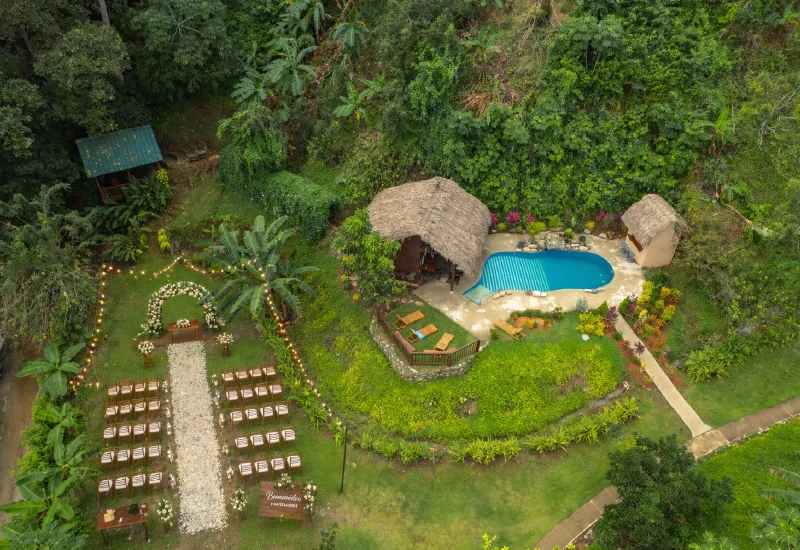 Aerial view of the poolside area at Promised Land Tayrona featuring a tropical wedding ceremony setup, luxury pool, lush gardens, and rainforest surroundings in Colombia.
